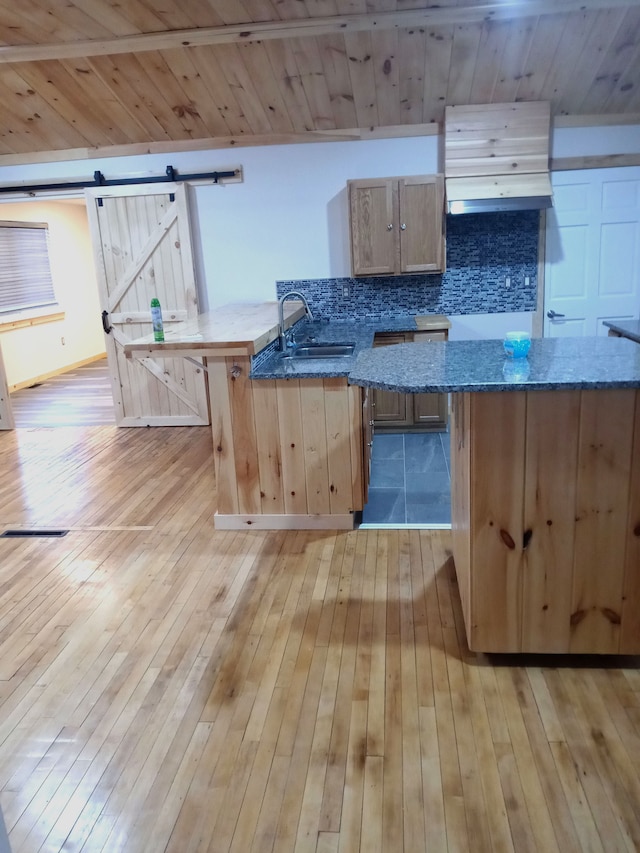 kitchen with a barn door, light hardwood / wood-style floors, sink, and light brown cabinetry