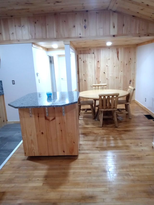 kitchen featuring stone counters, light hardwood / wood-style flooring, a center island, and lofted ceiling