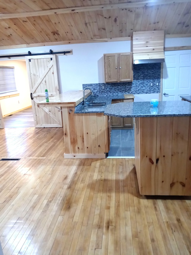 kitchen featuring light brown cabinetry, a barn door, light hardwood / wood-style floors, and sink