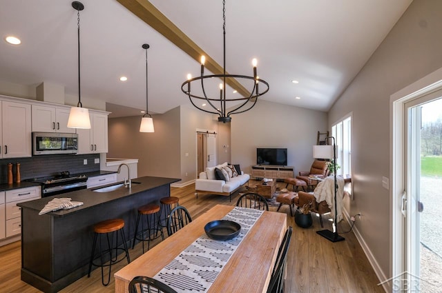 dining room featuring an inviting chandelier, light wood-type flooring, sink, and vaulted ceiling