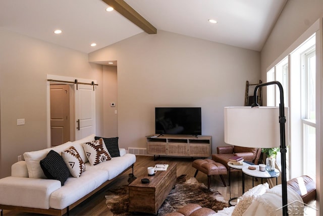 living room with hardwood / wood-style floors, vaulted ceiling with beams, and a barn door