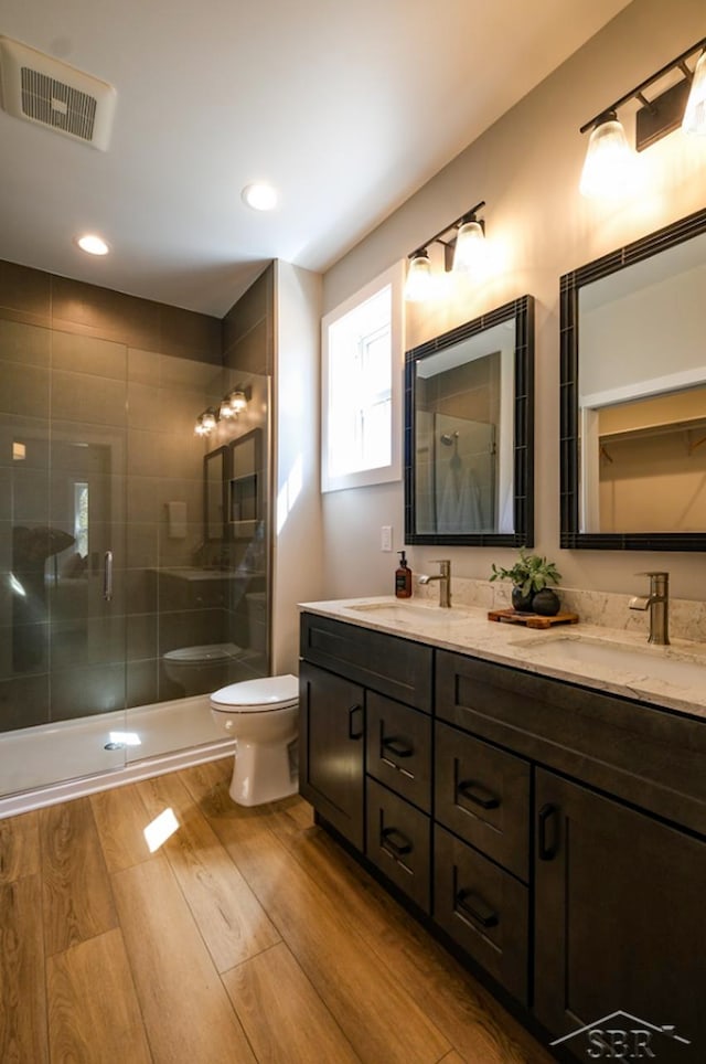 bathroom with a shower with door, vanity, wood-type flooring, and toilet