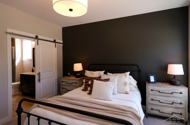 carpeted bedroom with a barn door and connected bathroom