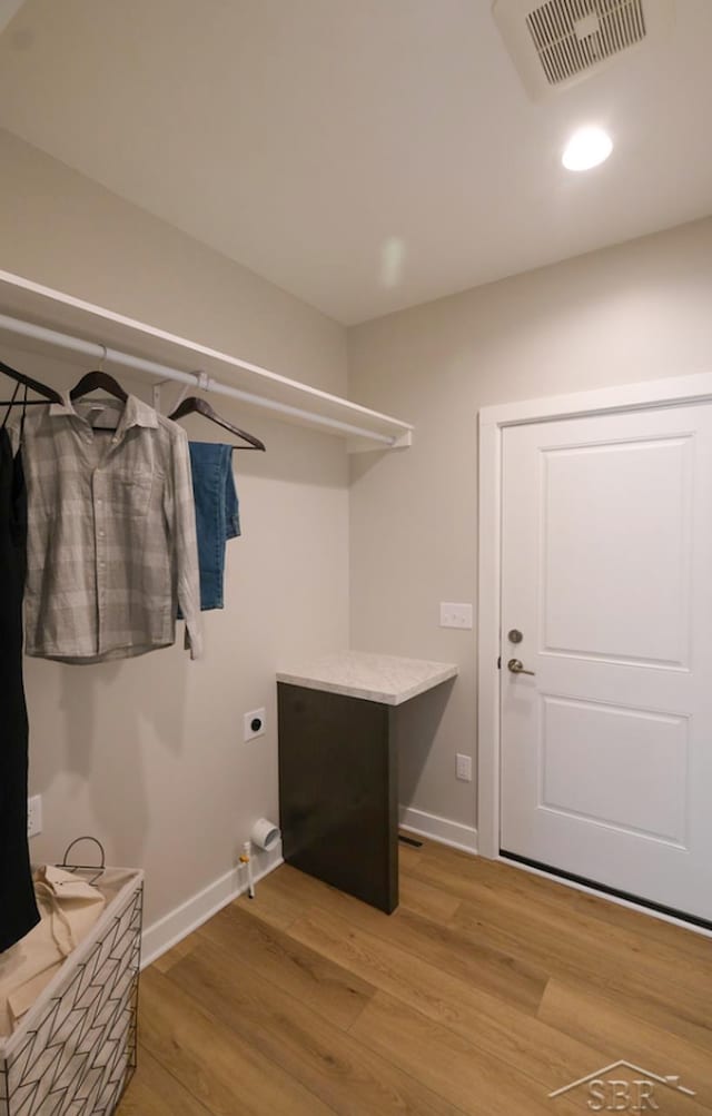 clothes washing area featuring electric dryer hookup and light wood-type flooring