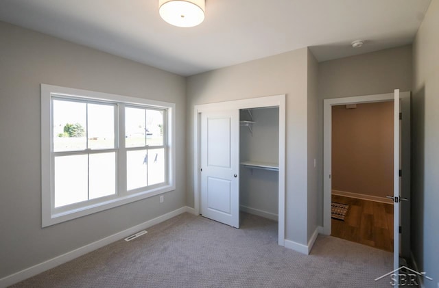 unfurnished bedroom with light carpet and a closet