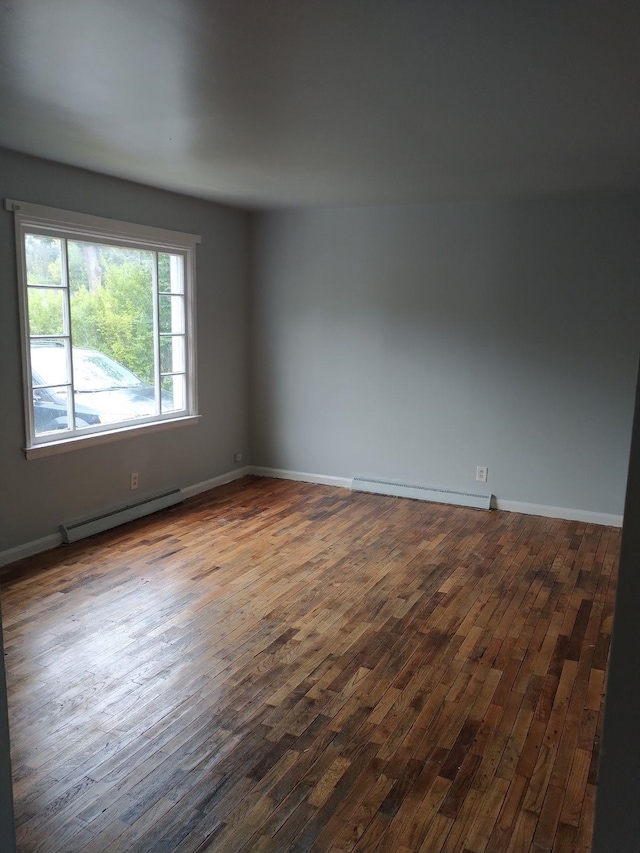 unfurnished room with hardwood / wood-style floors and baseboard heating