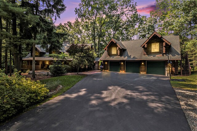 11245 Guyn Dr, Brighton, MI 48114 - log home featuring driveway, log exterior, roof with shingles, an attached garage, and stairs