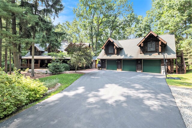 11245 Guyn Dr, Brighton, MI 48114 - log-style house featuring asphalt driveway, a garage, log exterior, and stairs