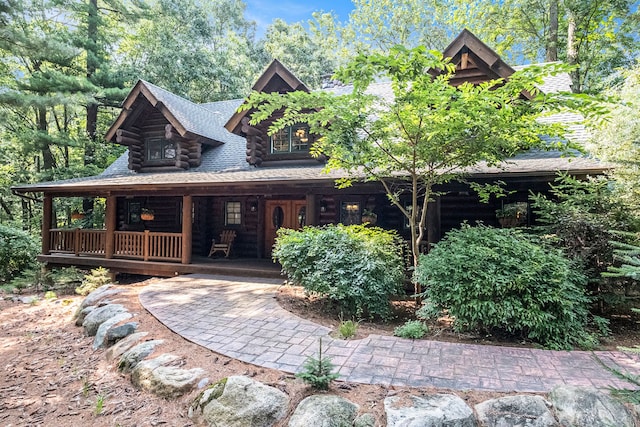 11245 Guyn Dr, Brighton, MI 48114 - view of front of property with log siding, a porch, and a shingled roof