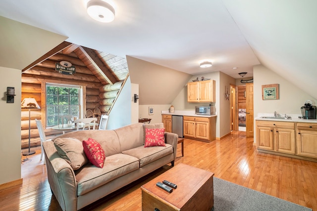 living room with light wood-type flooring, rustic walls, lofted ceiling, and sink