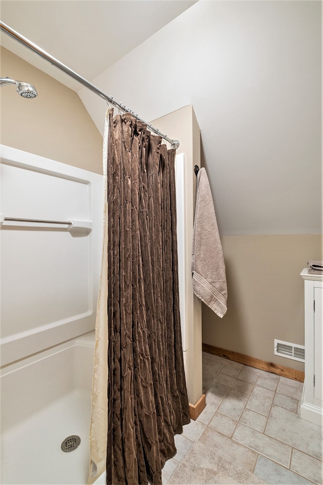 bathroom featuring tile patterned flooring, vaulted ceiling, and curtained shower