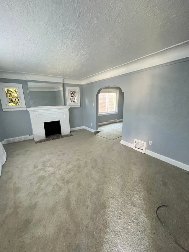 unfurnished living room featuring a fireplace, a textured ceiling, and carpet floors