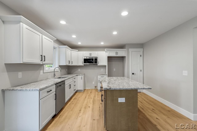 kitchen featuring light stone countertops, white cabinets, light wood-type flooring, and appliances with stainless steel finishes