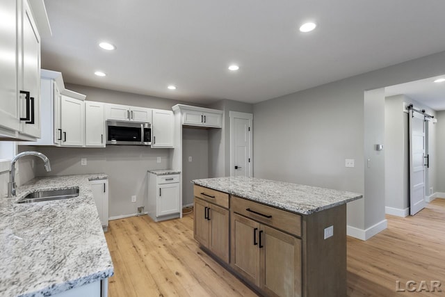 kitchen featuring white cabinets, a center island, a barn door, and sink