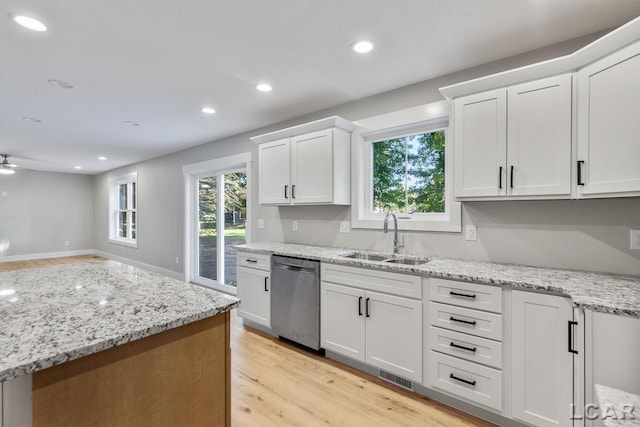 kitchen with white cabinets, light stone counters, sink, dishwasher, and light hardwood / wood-style floors