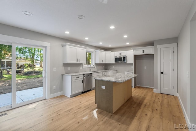 kitchen with a wealth of natural light, white cabinets, stainless steel appliances, and a kitchen island