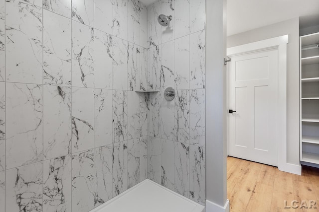 bathroom featuring hardwood / wood-style floors and a tile shower