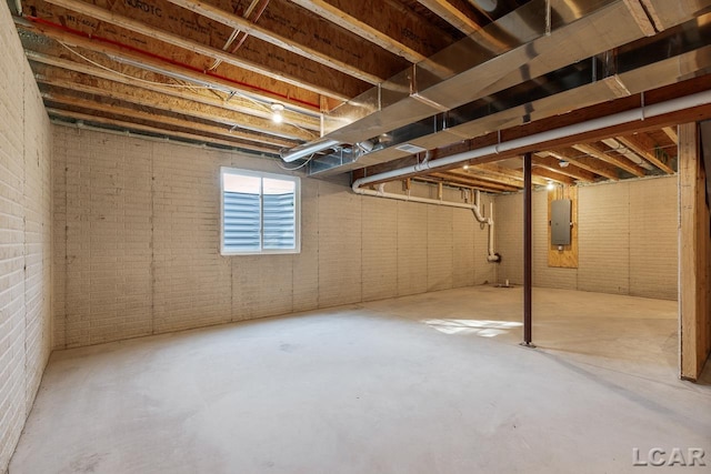 basement featuring electric panel and brick wall