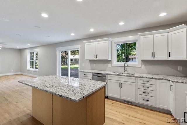 kitchen with light wood-type flooring, light stone counters, white cabinetry, and sink