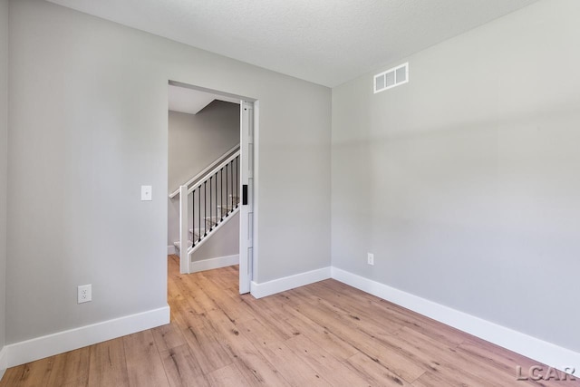 spare room with a textured ceiling and light wood-type flooring