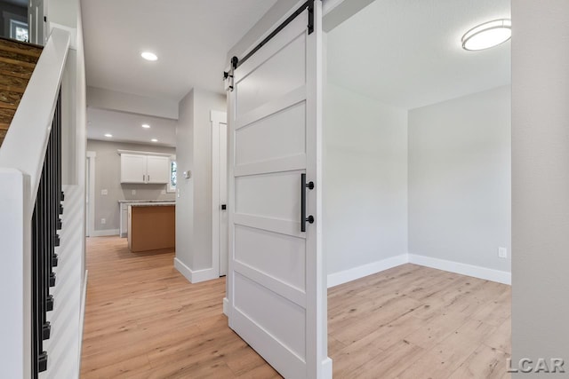 corridor with a barn door and light wood-type flooring