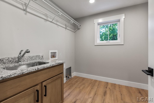 laundry area with cabinets, sink, washer hookup, and light wood-type flooring