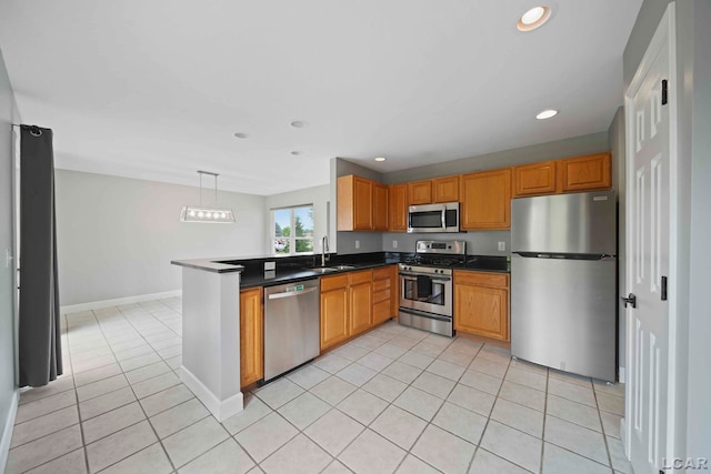 kitchen with kitchen peninsula, appliances with stainless steel finishes, sink, light tile patterned floors, and hanging light fixtures