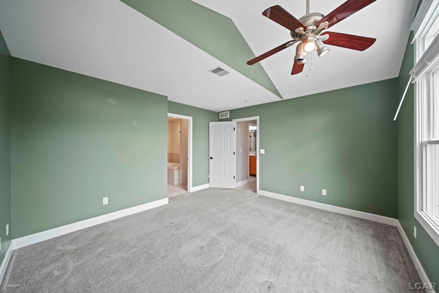 unfurnished bedroom with ensuite bath, ceiling fan, light colored carpet, and vaulted ceiling