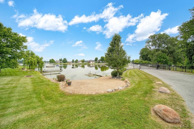 view of property's community with a water view and a lawn