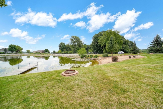 view of yard featuring a water view, a dock, and an outdoor fire pit