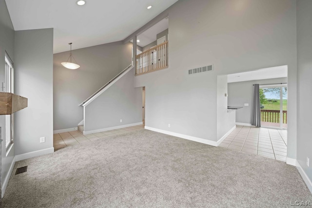 unfurnished living room with light colored carpet and high vaulted ceiling