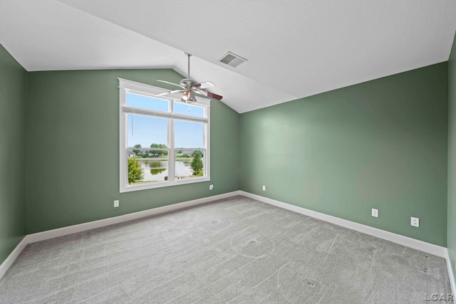 carpeted spare room with ceiling fan, a water view, and vaulted ceiling