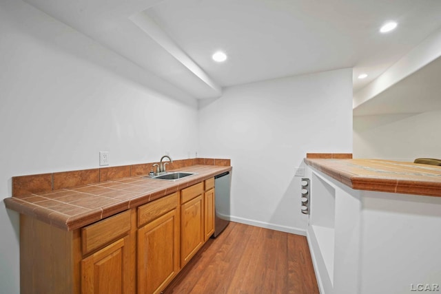 kitchen featuring dishwasher, hardwood / wood-style flooring, tile counters, and sink