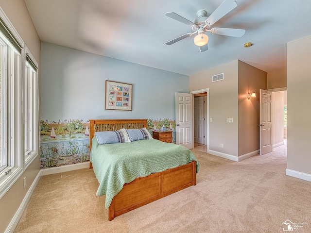 bedroom featuring multiple windows, light colored carpet, and ceiling fan