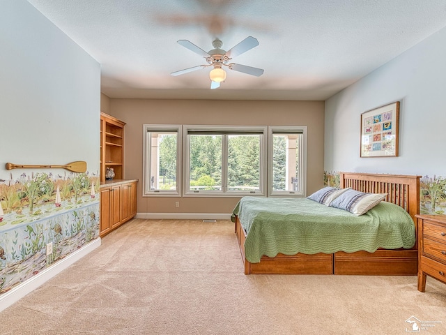 bedroom with a textured ceiling, light colored carpet, and ceiling fan