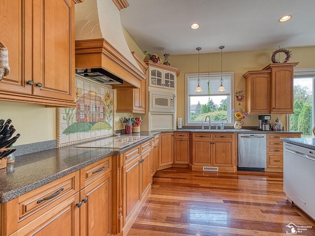 kitchen featuring stainless steel dishwasher, custom exhaust hood, white microwave, and a wealth of natural light