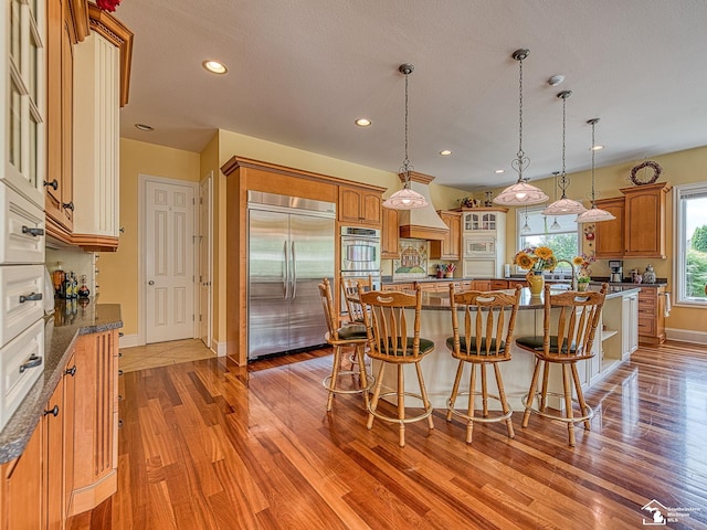 kitchen featuring hanging light fixtures, a kitchen island, stainless steel appliances, and light hardwood / wood-style floors