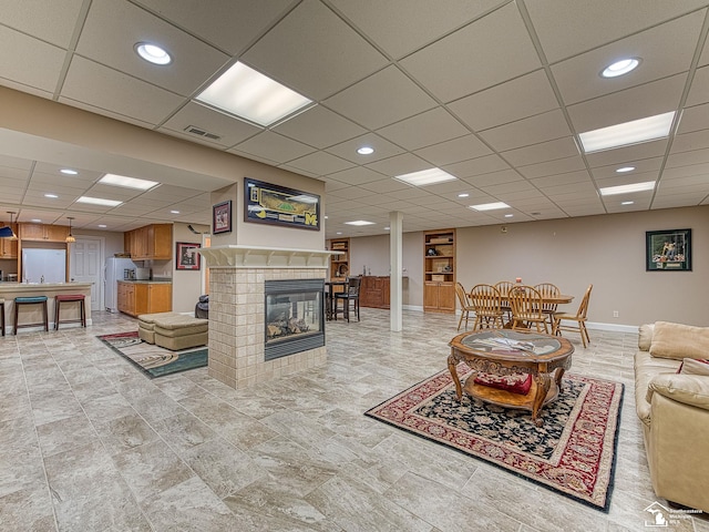 living room with a tile fireplace and a paneled ceiling