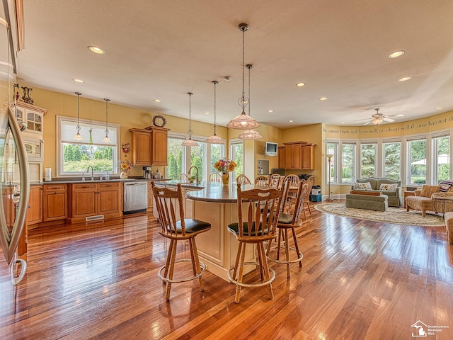 kitchen featuring sink, light hardwood / wood-style flooring, ceiling fan, appliances with stainless steel finishes, and a kitchen bar