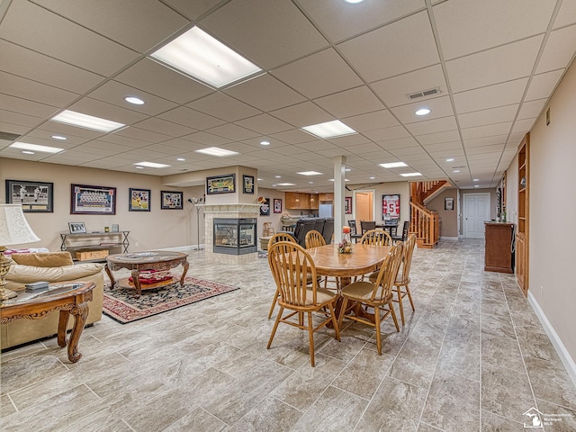 dining area with a tiled fireplace and a paneled ceiling