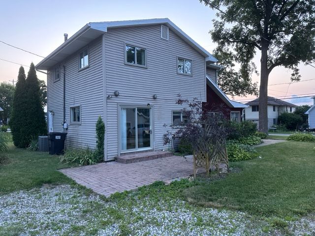 back house at dusk featuring a patio and a lawn