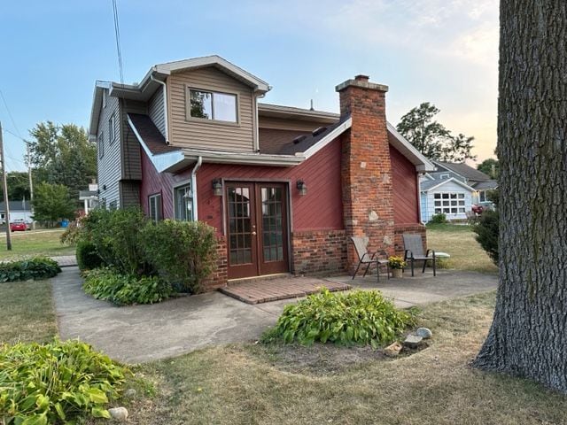 back house at dusk featuring a patio area, a yard, and french doors