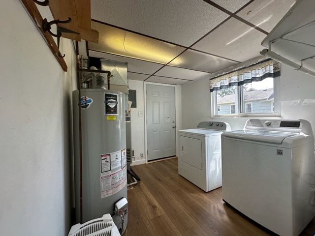 laundry area with dark hardwood / wood-style floors, washer and clothes dryer, and water heater