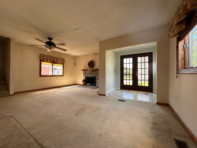 unfurnished living room with french doors, a textured ceiling, and a healthy amount of sunlight