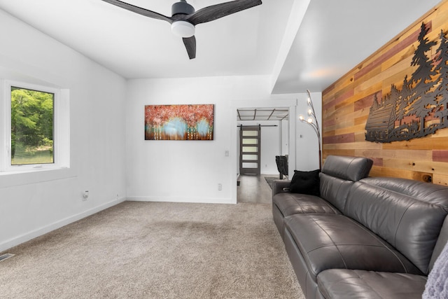 living room featuring wood walls, carpet, and ceiling fan