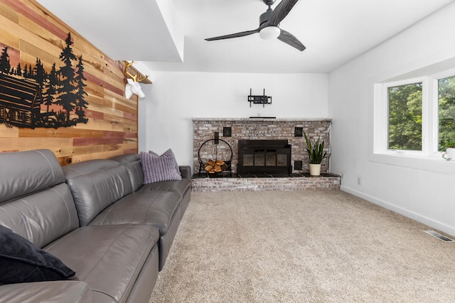 living room with carpet flooring, wooden walls, a fireplace, and ceiling fan