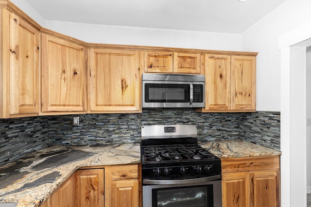 kitchen with light stone counters, appliances with stainless steel finishes, and tasteful backsplash