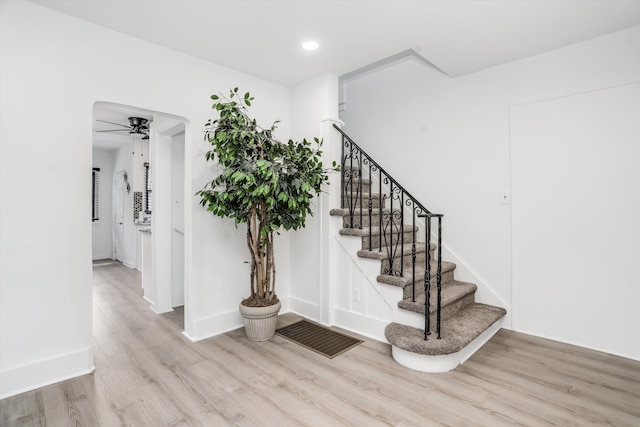 stairway featuring ceiling fan and hardwood / wood-style flooring