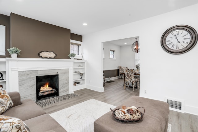 living room with light hardwood / wood-style flooring and a tiled fireplace