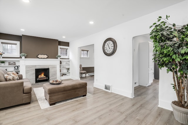 living room with a fireplace and light wood-type flooring